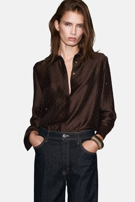 Bruin overhemd met lange mouwen van MANGO, met stippenpatroon en geplooide details, gedragen met een donkerblauwe jeans.