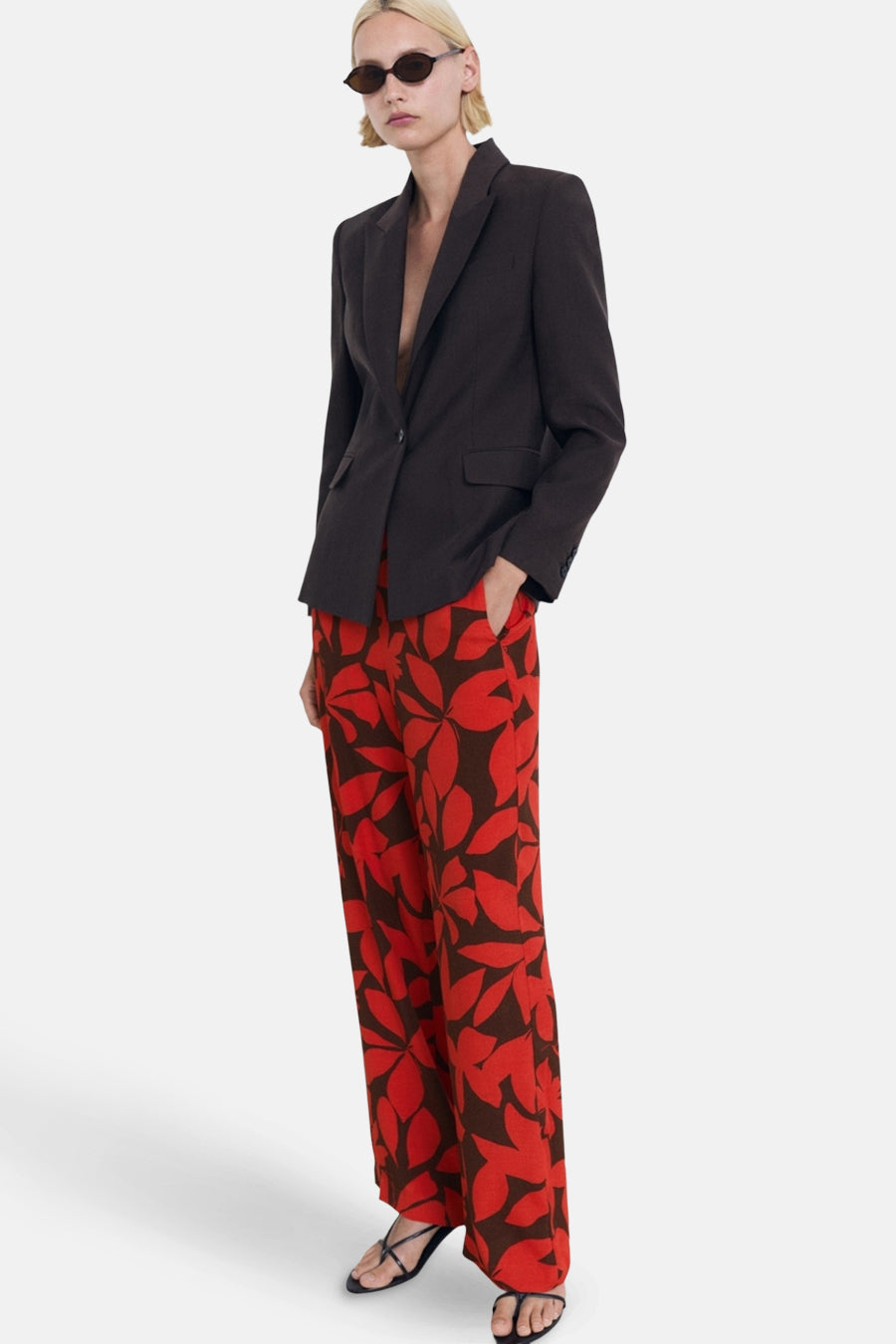 Multikleurige broek van MANGO, met een patroon van grote rode en bruine bladeren.