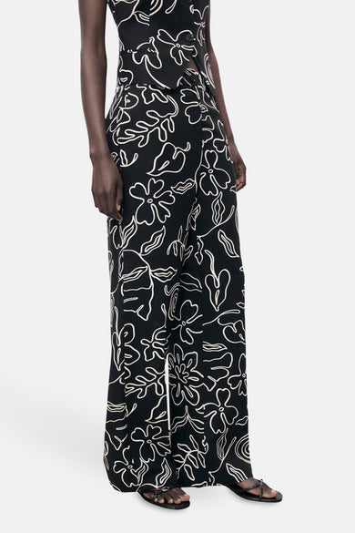 Zwarte broek met wit bloemenpatroon van MANGO, wijde pasvorm, gedragen met een bijpassend topje en sandalen.