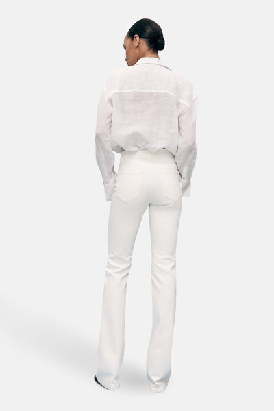 Witte uitlopende jeans van MANGO, gedragen met een losvallend wit linnen overhemd, van achteren gezien.