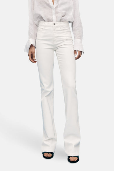 Witte flared jeans van MANGO, gedragen met een wit overhemd en zwarte schoenen.