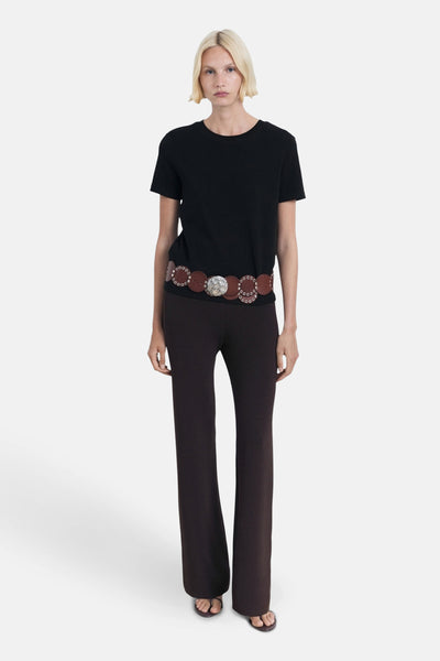 Zwart T-shirt met korte mouwen van MANGO, gedragen met een bruine riem met ronde versieringen en een bruine broek.