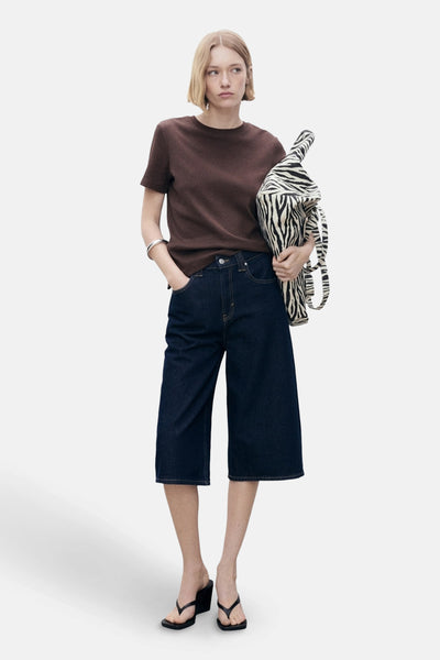 Bruin T-shirt met korte mouwen van MANGO, gedragen met een spijkerbroek tot halverwege de kuit en een tas met zebraprint.