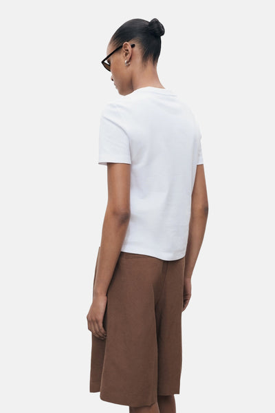 Wit T-shirt met korte mouwen van MANGO, gedragen met een bruine capribroek, achtergezicht.