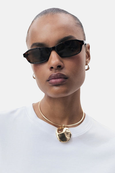 T-shirt à manches courtes blanc de MANGO, porté avec un collier doré à pendentif.

