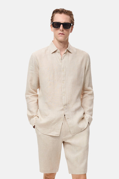 Beige overhemd met lange mouwen van MANGO, gedragen met een zwarte zonnebril en een bijpassende korte broek.