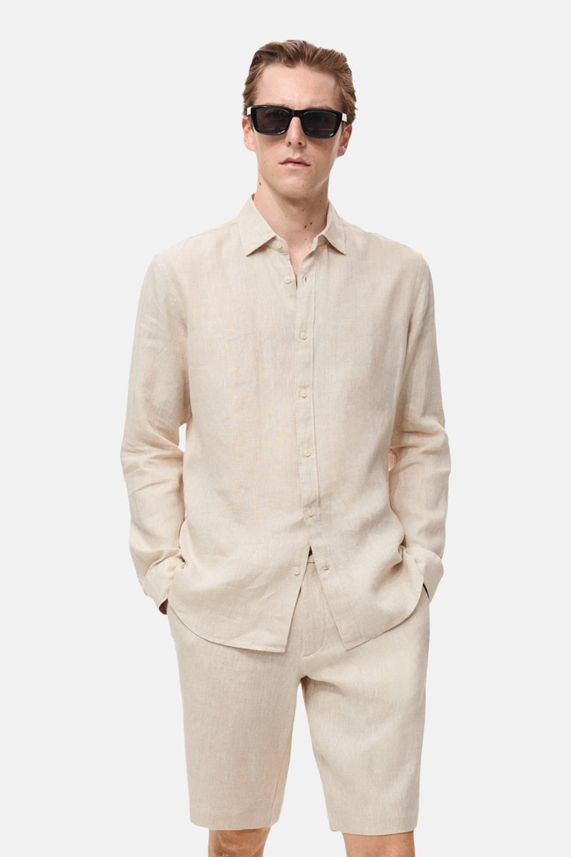 Beige overhemd met lange mouwen van MANGO, gedragen met een zwarte zonnebril en een bijpassende korte broek.