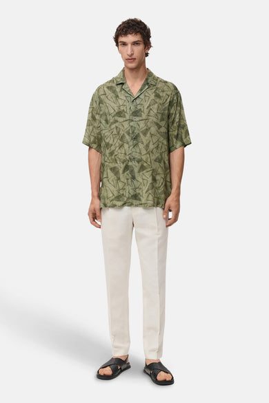 Groen overhemd met korte mouwen van MANGO, met geometrische print, gedragen met een beige broek en zwarte sandalen.