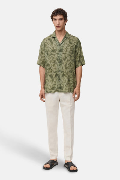 Groen overhemd met korte mouwen van MANGO, met geometrische print, gedragen met een beige broek en zwarte sandalen.