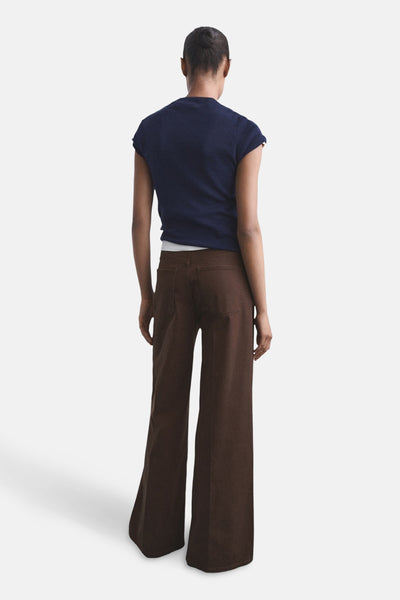 Jean coloré brun de MANGO, coupe ample et jambes larges, porté avec un t-shirt bleu marine.