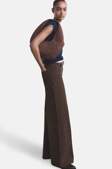 Gekleurde bruine jeans van MANGO, wijde pasvorm, gedragen met een bruine schoudertas en een marineblauwe top.
