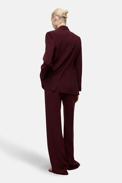Pantalon de costume bordeaux de MANGO, coupe droite fluide, tombant sur des sandales.