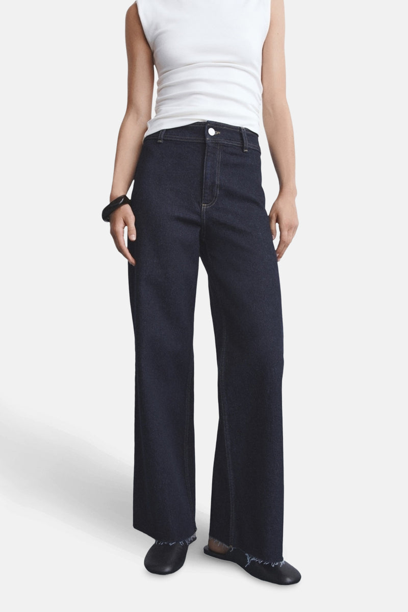 Jean large en denim bleu foncé de MANGO, porté avec un t-shirt blanc et des chaussures noires.
