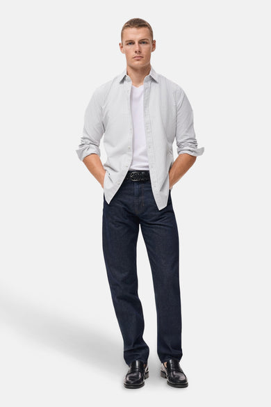 Multikleurig overhemd met lange mouwen van MANGO, gedragen open over een wit T-shirt en een donkere spijkerbroek.