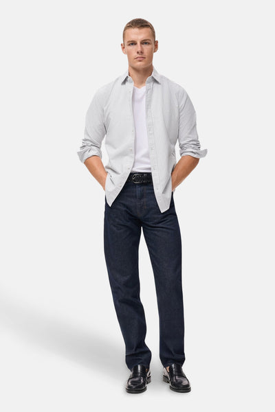 Multikleurig overhemd met lange mouwen van MANGO, gedragen open over een wit T-shirt en een donkere spijkerbroek.