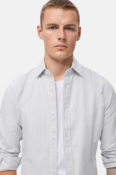Gestreepte katoenen blouse met lange mouwen van MANGO, open gedragen over een wit T-shirt.