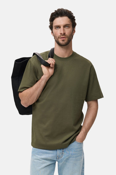 Kaki T-shirt met korte mouwen van MANGO, gedragen met een lichtblauwe jeans en een zwarte schoudertas.