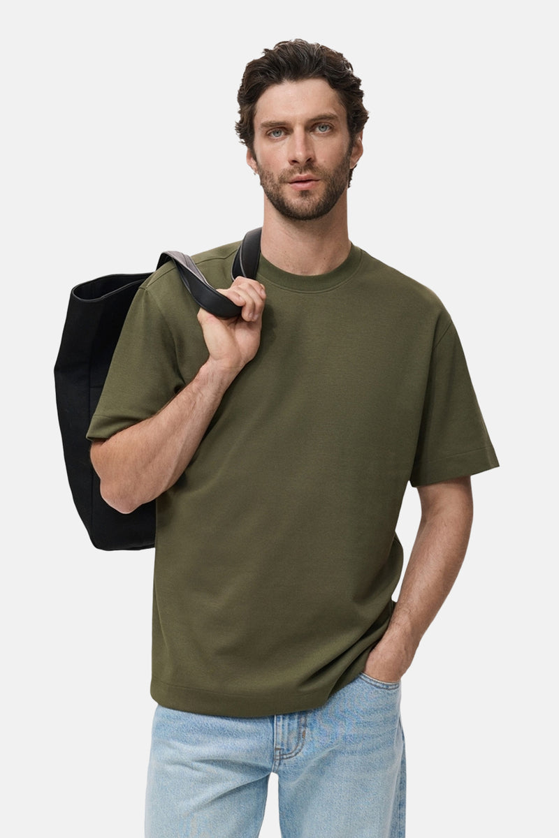 Kaki T-shirt met korte mouwen van MANGO, gedragen met een lichtblauwe jeans en een zwarte schoudertas.