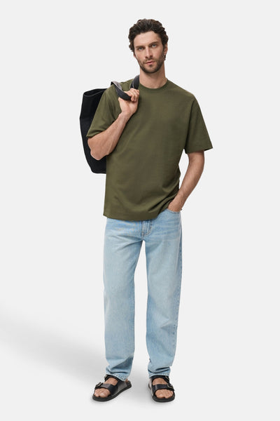 Kaki T-shirt met korte mouwen van MANGO, gedragen met een lichtblauwe jeans en zwarte sandalen.