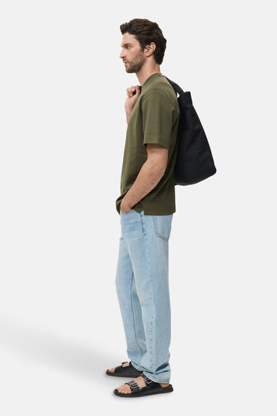 Kaki T-shirt met korte mouwen van MANGO, gedragen met een lichte spijkerbroek en zwarte sandalen, zijwaarts bekeken.