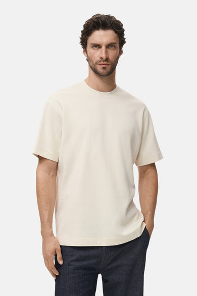 Beige T-shirt met korte mouwen van MANGO, gedragen met een marineblauwe spijkerbroek.