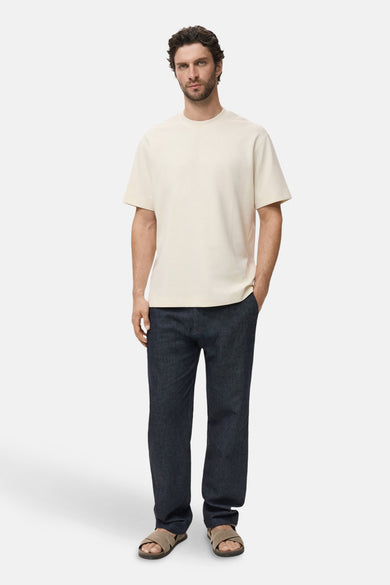Beige T-shirt met korte mouwen van MANGO, gedragen met een donkerblauwe broek en bruine sandalen.