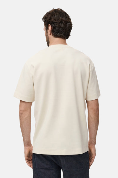 Beige T-shirt met korte mouwen van MANGO, van achteren gezien, gedragen met een donkere broek.