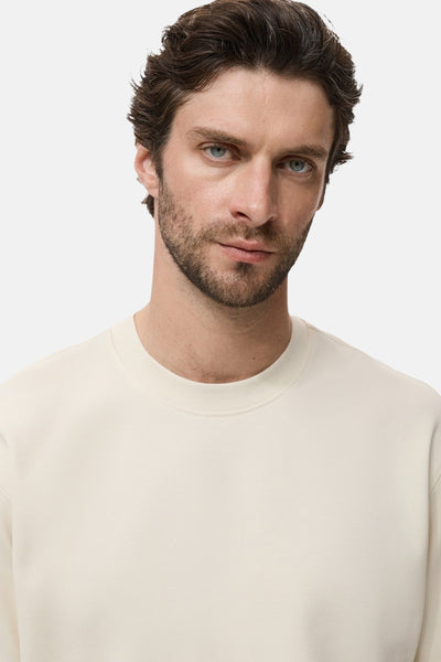 Beige T-shirt met korte mouwen van MANGO, gedragen door een man met een baard.