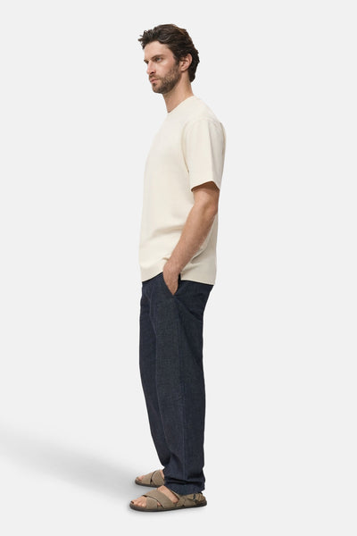 Beige T-shirt met korte mouwen van MANGO, gedragen met een donkerblauwe broek en gekruiste sandalen.