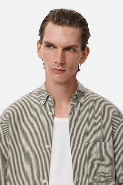 Chemise kaki à rayures verticales de MANGO, portée ouverte sur un t-shirt blanc.
