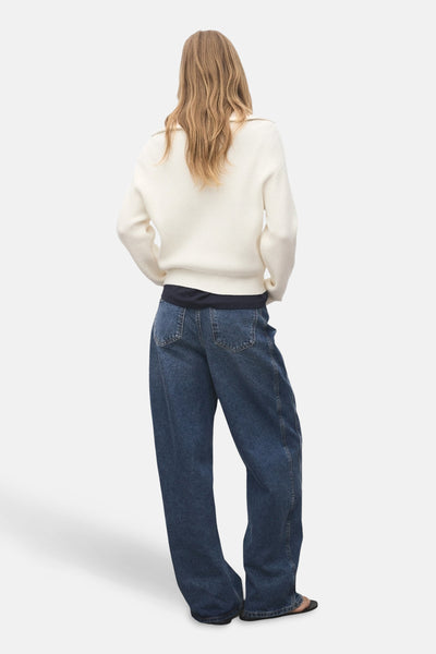 Witte coltrui van MANGO, getextureerd in ribgebreid, gedragen met een wijde spijkerbroek.