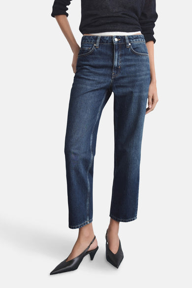 Rechte donkerblauwe spijkerbroek van MANGO, gedragen met zwarte pumps en een korte trui.