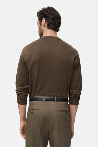 Kaki T-shirt met lange mouwen van MANGO, gedragen met een zwarte broek en riem, achterzijde.