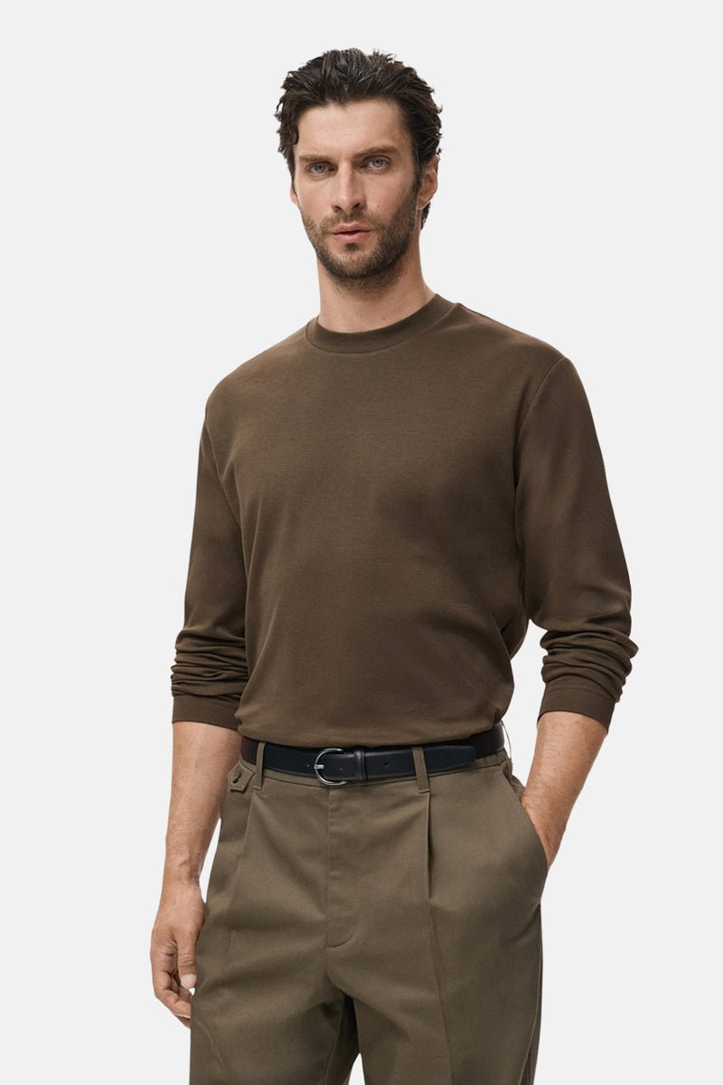 Kaki T-shirt met lange mouwen van MANGO, gedragen met een zwarte broek en riem.