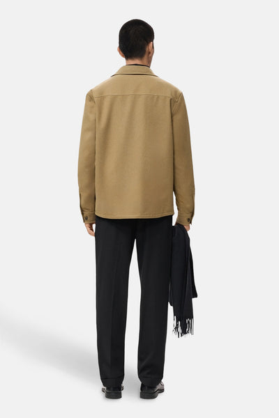 Kort bruin jasje van MANGO, van achteren gezien, gedragen met een zwarte broek en een donkere sjaal.