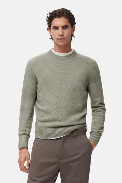 Pull col rond vert par MANGO, porté sur un t-shirt blanc et un pantalon marron, avec une texture douce.