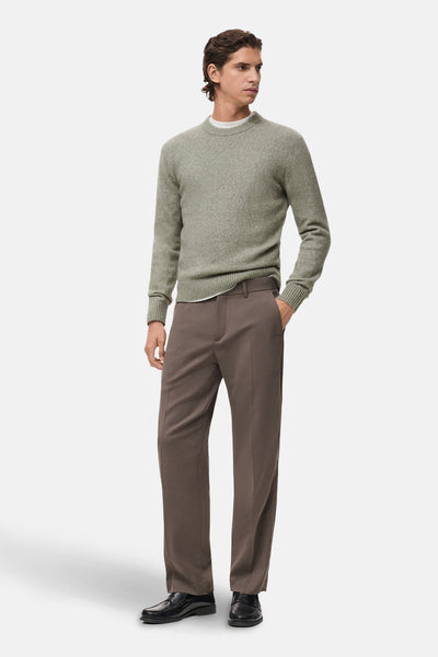 Pull col rond vert de MANGO, porté avec un pantalon marron et des mocassins noirs.