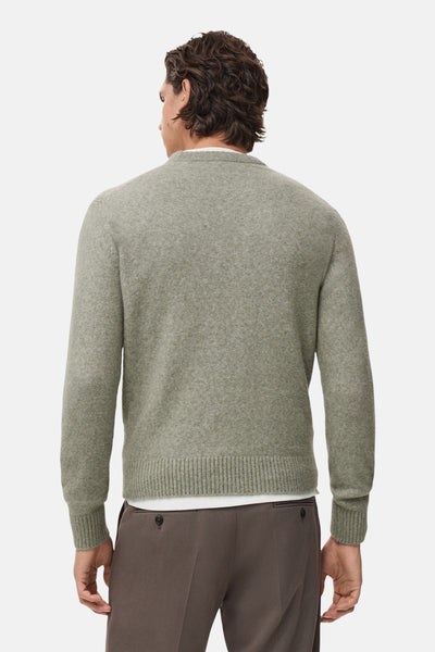 Pull col rond vert de MANGO, vue de dos, porté sur un t-shirt blanc et un pantalon marron.