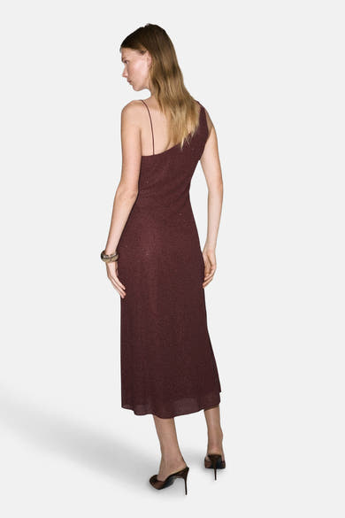 Robe bordeaux à une épaule de MANGO, avec un motif à pois et portée avec des mules à talons.
