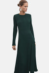 Robe vert à manches longues de MANGO, avec des détails structurés et des boucles d'oreilles géométriques.
