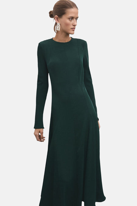 Groene jurk met lange mouwen van MANGO, met een uitlopende pasvorm en bijpassende pumps, van achteren gezien.