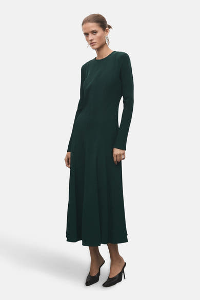 Robe longue verte à manches longues de MANGO, portée avec des escarpins noirs.