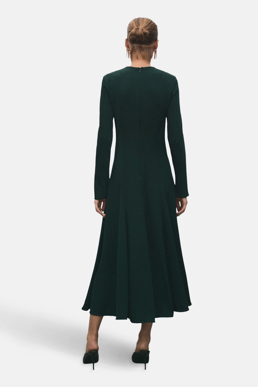 Robe à manches longues verte de MANGO, avec une coupe évasée et des escarpins assortis, vue de dos.
