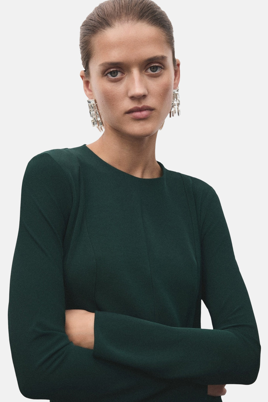 Robe verte à manches longues de MANGO, avec des boucles d'oreilles pendantes argentées.