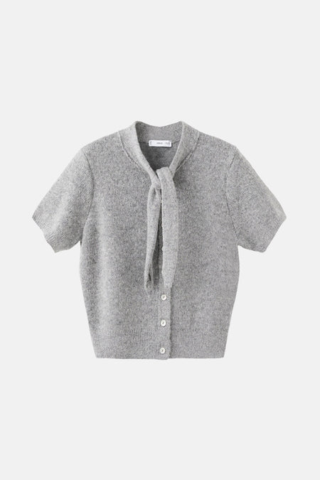 Grijze bodywarmer van MANGO, gedragen met een bruine wollen broek en een suède jas.