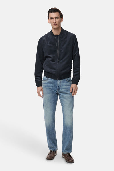 Veste courte bleue de MANGO, avec une fermeture éclair et portée avec un jean et des chaussures marron.