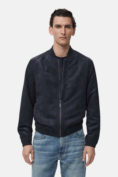Veste courte bleue en daim de MANGO, avec fermeture éclair argentée et poches discrètes, portée avec un jean.