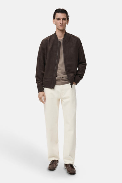 Veste courte brune par MANGO, avec fermeture éclair, portée avec un t-shirt beige et un pantalon écru.