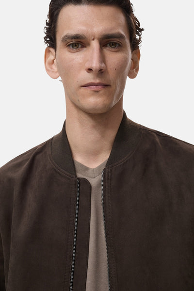 Veste courte brune by MANGO, avec fermeture éclair et col montant, portée sur un t-shirt beige.
