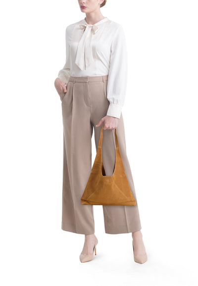 Sac à bandoulière marron de MANGO, porté avec un pantalon beige et un chemisier blanc.